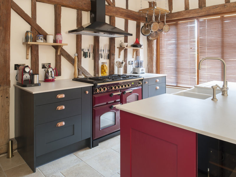 red kitchen with range cooker and beams