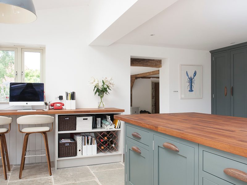green kithen with wood worktops and stone floor