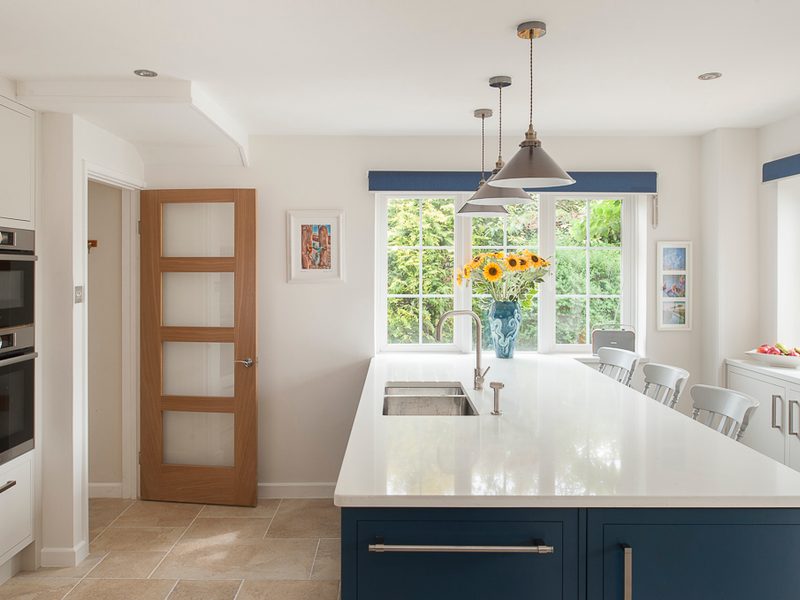 light airy kitchen with blue island and white worktops