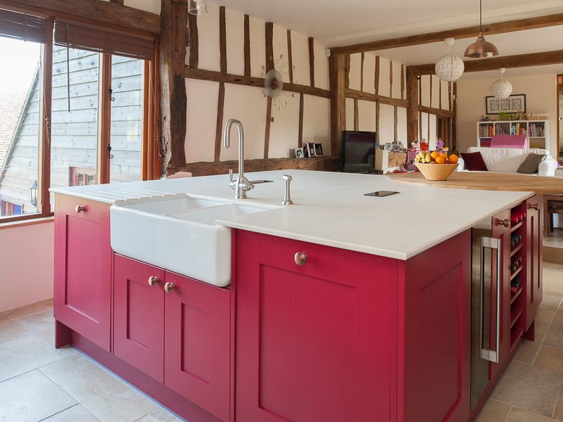 red kitchen island with belfast sink and beams