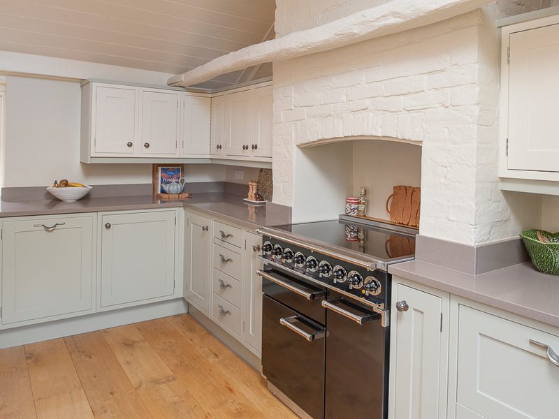 green kitchen with brick chimney and range cooker