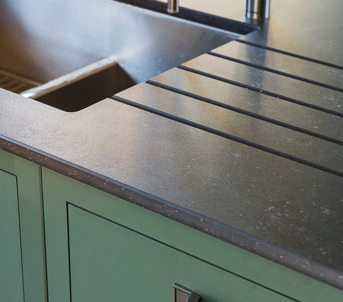 green kitchen with swan neck tap and dark worktops