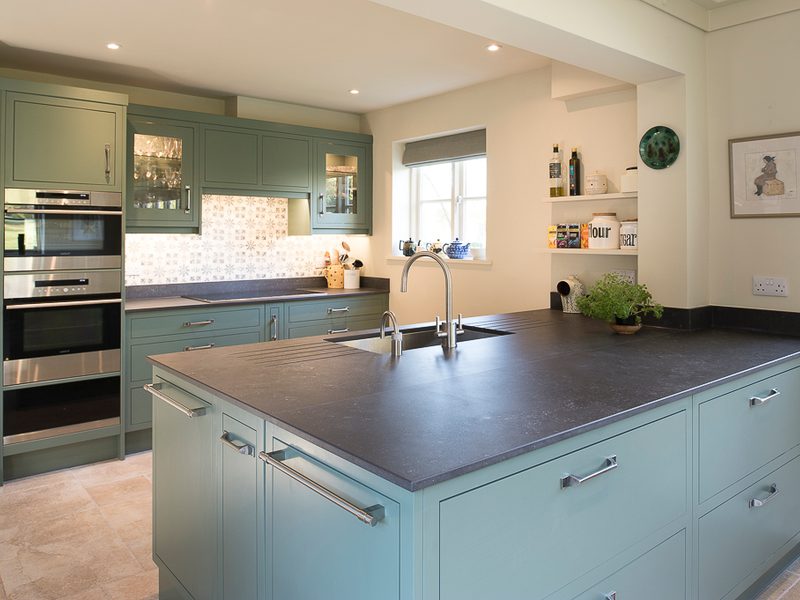 green kitchen with island and dark worktops
