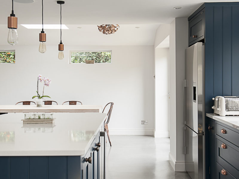 modern blue kitchen with pendant lamps and white worktop